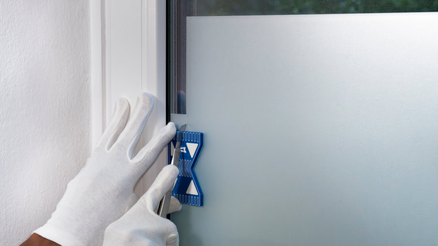 Versatzschneider-961 beim Zuschneiden von Sichtschutzfolie an einer Fenster-Innenkante. Erlaubt präzise Schnittbreiten durch stabile Führung.