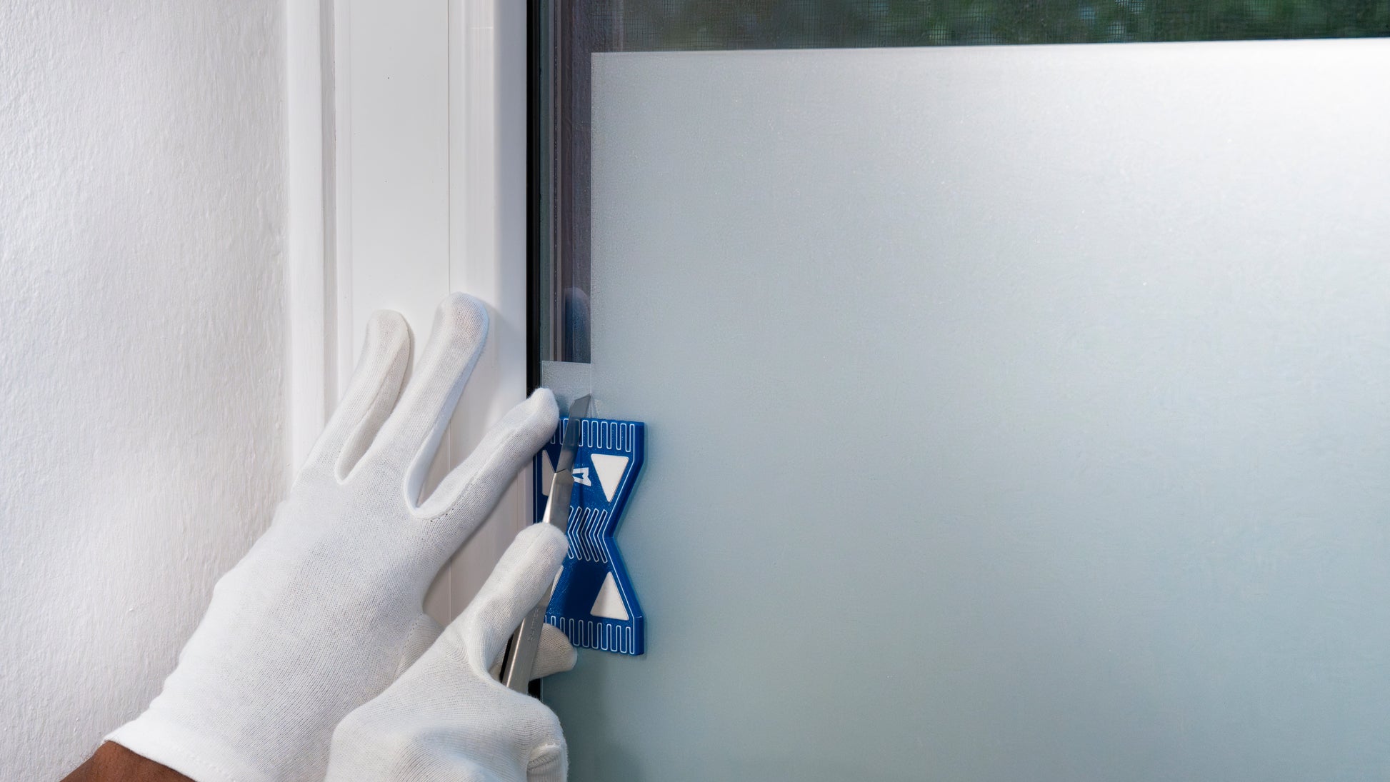 Versatzschneider-961 beim Zuschneiden von Sichtschutzfolie an einer Fenster-Innenkante. Erlaubt präzise Schnittbreiten durch stabile Führung.
